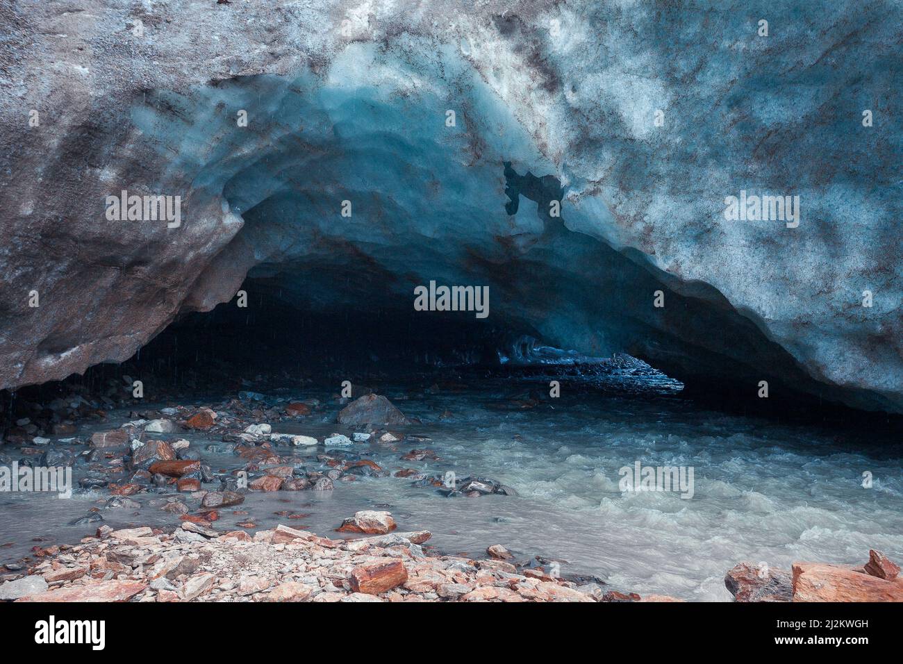 Sortie de la grotte de glace bleue sculptée dans le glacier de Vallelunga traversé par un ruisseau Banque D'Images