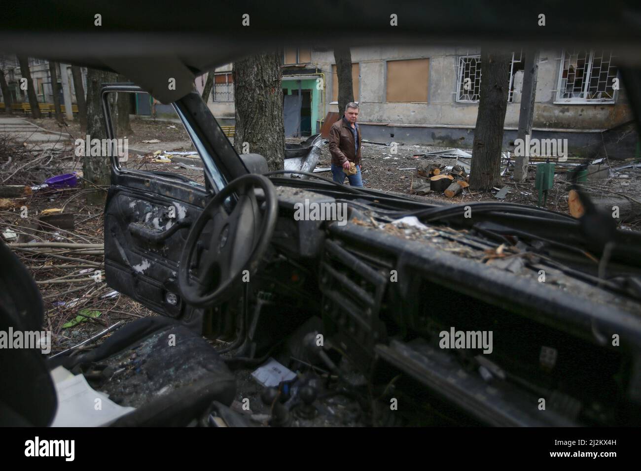 Un homme passé d'une voiture civile brûlée le 1 avril 2022 à Kharkiv, en Ukraine. Banque D'Images