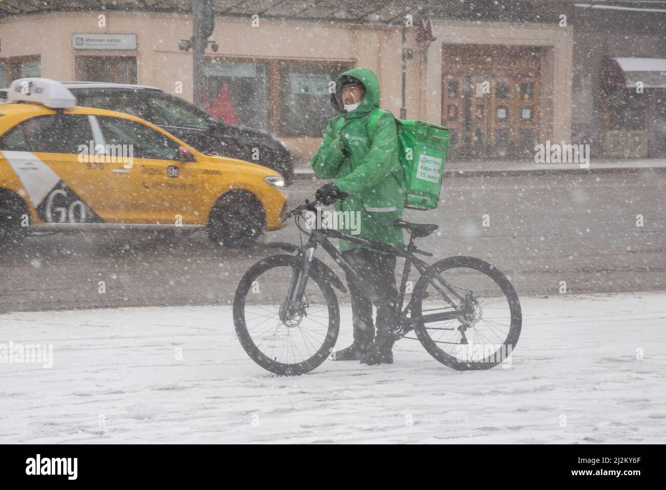 Moscou, Russie. 2nd avril 2022. Un service de livraison de nourriture par messagerie 'Delivery Club' livre une commande sur la rue Tverskaya dans le centre de Moscou pendant une tempête de neige, en Russie. Banque D'Images