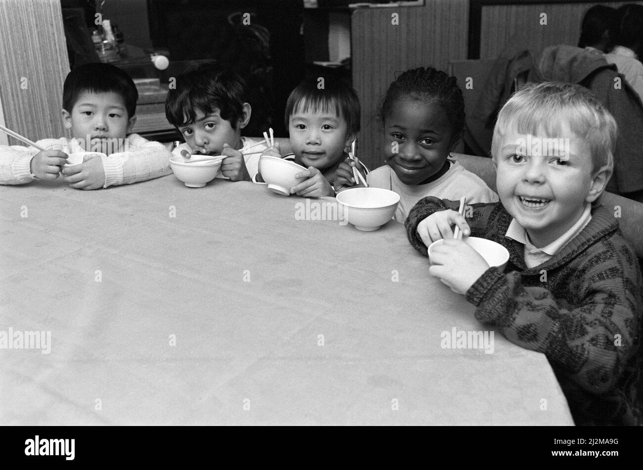 Les enfants chinois, Hom Wah Ho (à gauche) et William Cheung (au centre), n'ont tout simplement pas compris ce qu'était l'agitation quand ils ont fait une sortie scolaire dans un restaurant chinois. Mais ils n'ont pas pu résister à un rire car leurs amis de Spring Grove Junior, les nourrissons et la nursery School fumirent avec leurs baguettes. Ils sont photographiés avec (à partir de la gauche) Fraz Shaffi, Lissa gay et Craig Murphy. Hom, William et les autres élèves ont apprécié leur visite au restaurant chinois Cherry Tree - un régal pour le début de l'année chinoise du serpent. Environ 30 enfants, tous âgés de cinq ans, sont allés au restaurant af Banque D'Images