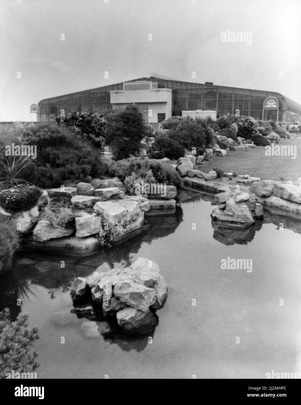 Rhyl Sun Center, Rhyl, pays de Galles du Nord. Jardins fleuris et étangs sur la promenade Rhyl avec le centre du soleil en arrière-plan. Vers 1991. Banque D'Images