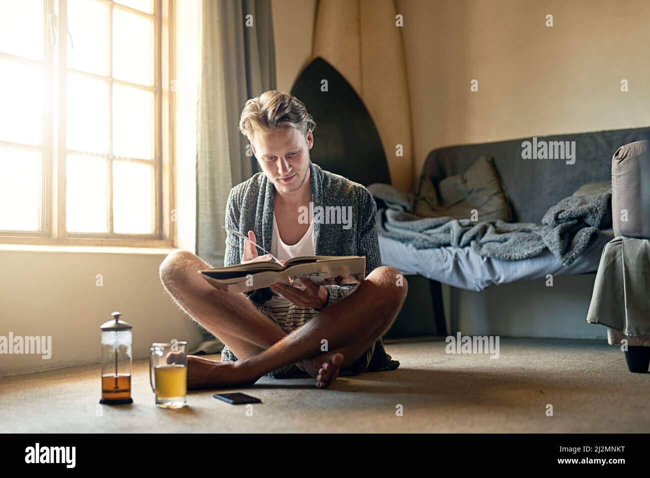 Rien ne vaut un bon page-turner. Photo d'un jeune homme lisant un livre à la maison. Banque D'Images