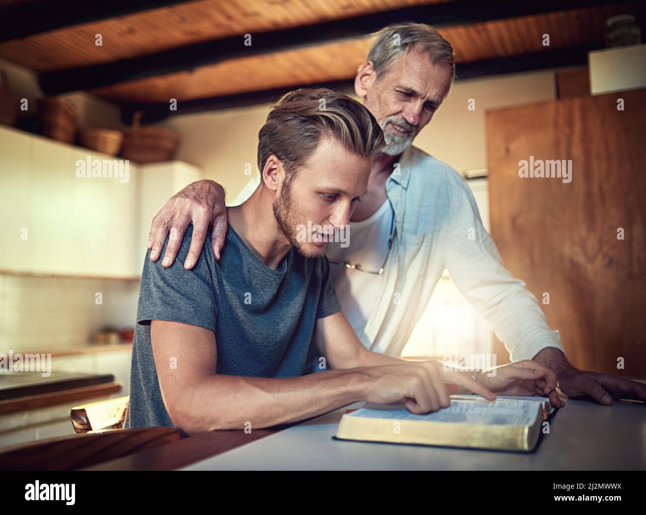 C'est une famille qui s'est renforcée dans la foi. Photo d'un père et d'un fils qui font l'étude de la Bible ensemble à la maison. Banque D'Images