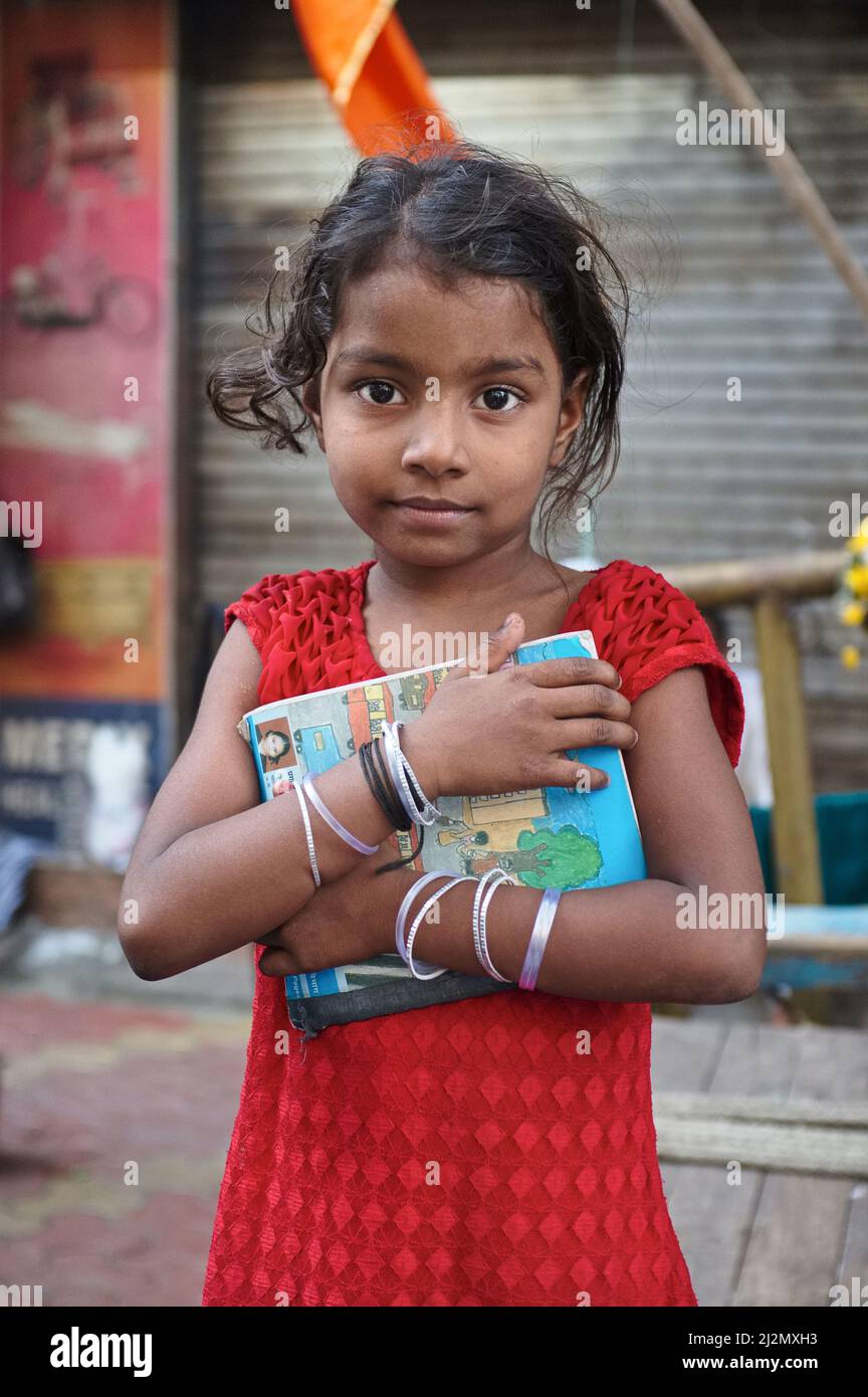 Une jeune fille à Mumbai, en Inde, vivant avec sa famille appauvrie sur un sentier (trottoir) à Kalbajevi Rd / Bhuleshwar, encombrant un livre scolaire Banque D'Images