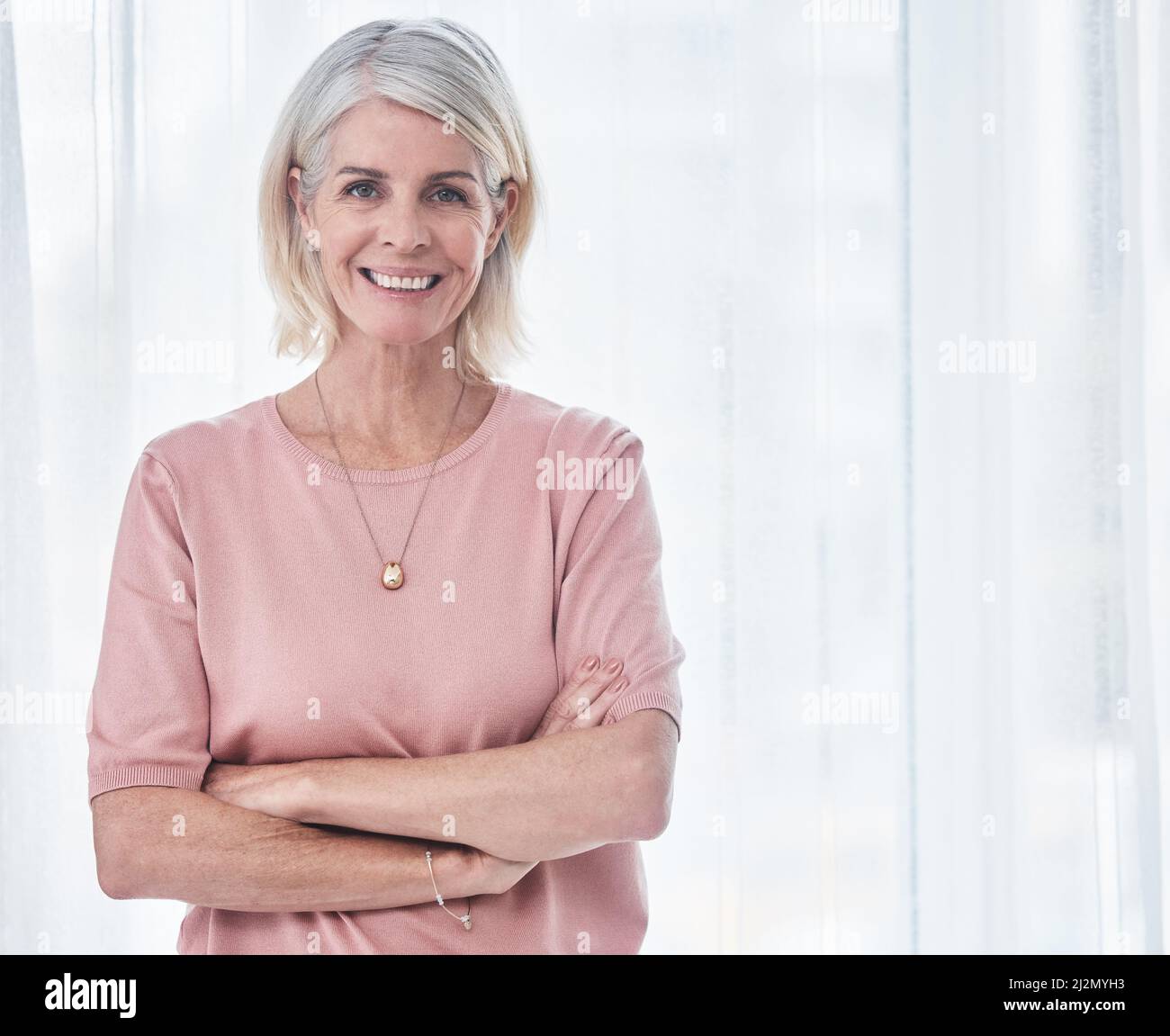 Je suis prêt à avoir un Bonne journée. Photo d'une femme âgée debout avec ses bras croisés tout en souriant à l'appareil photo. Banque D'Images