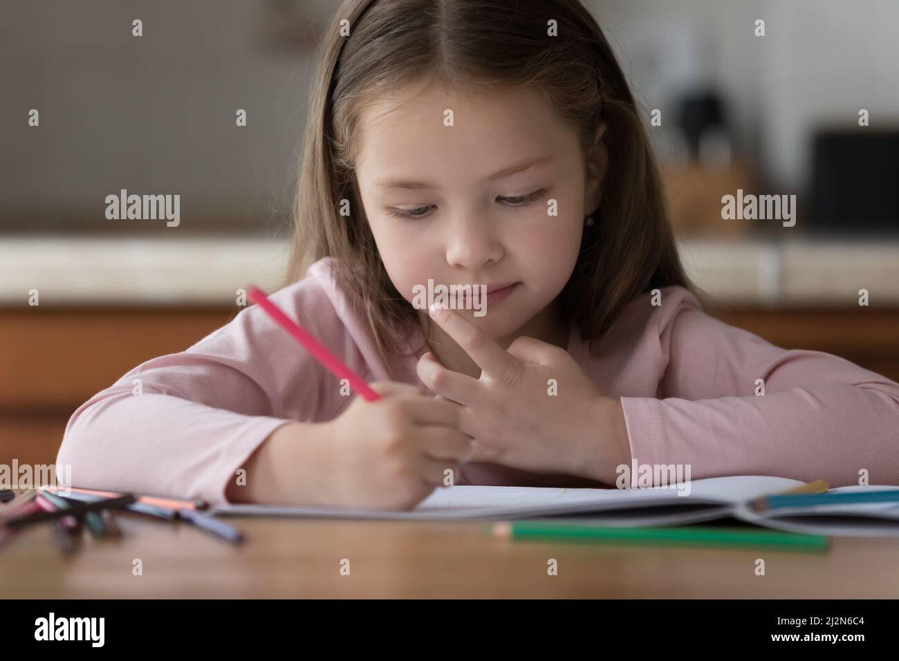 Enfant doux utilisant des crayons de couleur, dessin dans un album papier Banque D'Images