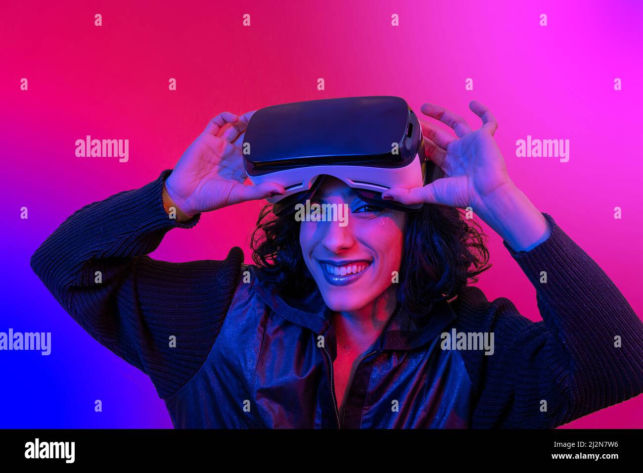 La jeune femme utilise le visualiseur de réalité virtuelle. Portrait d'une femme moderne souriante avec un look tendance et des couleurs vives. Banque D'Images