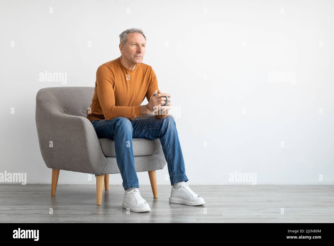 Homme ayant le repos à la maison assis sur une chaise, buvant du café Banque D'Images