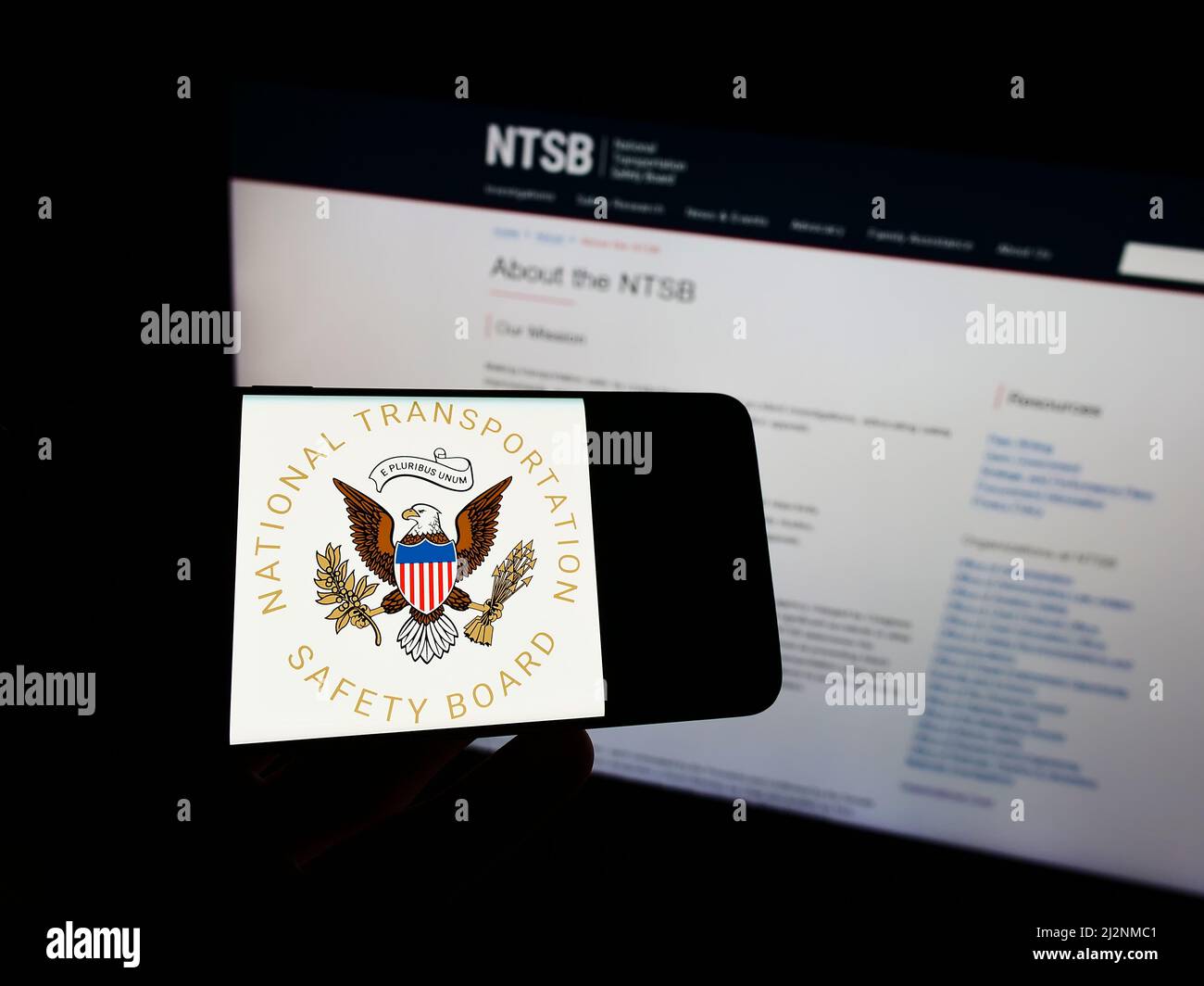 Personne tenant un téléphone portable avec le sceau du National Transportation Safety Board (NTSB) des États-Unis sur l'écran en face de la page Web. Mise au point sur l'affichage du téléphone. Banque D'Images Personne tenant un téléphone portable avec le sceau du National Transportation Safety Board (NTSB) des États-Unis sur l'écran en face de la page Web. Mise au point sur l'affichage du téléphone. Banque D'Images