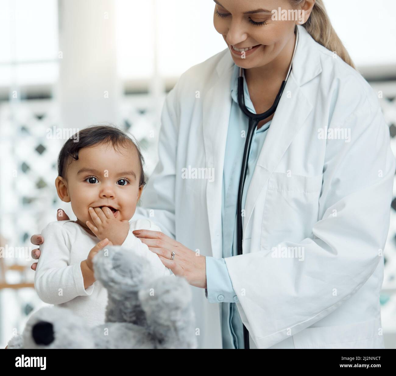 Elle a sa peluche pour apporter son confort. Photo d'un pédiatre examinant un bébé dans une clinique. Banque D'Images