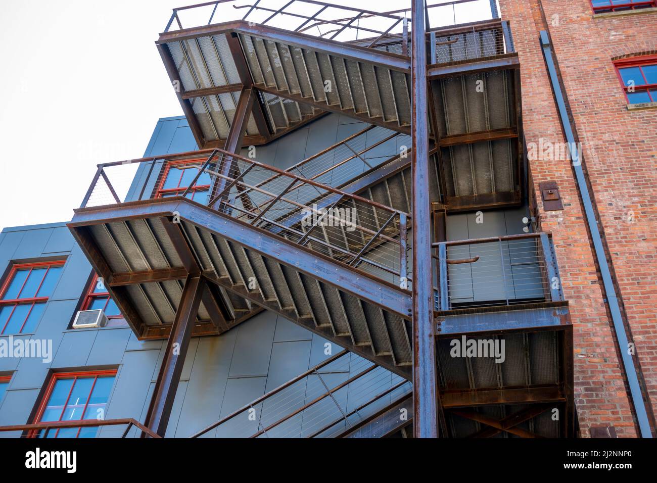 Vue à angle bas d'un escalier en bois à l'extérieur d'un bâtiment en brique rouge, menant à différents niveaux d'un appartement ou d'affaires Banque D'Images