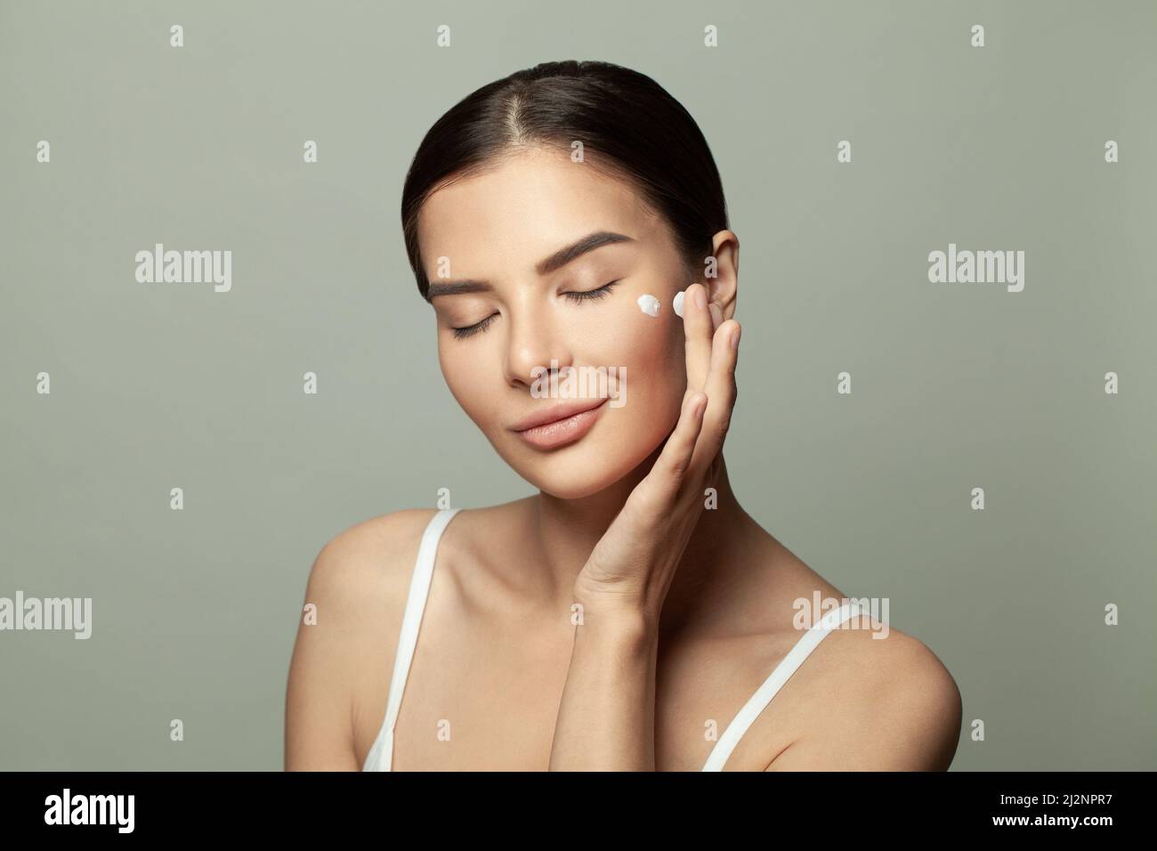 Femme en bonne santé appliquant de la crème hydratante sur son visage. Concept de traitement du visage et de soins de santé Banque D'Images