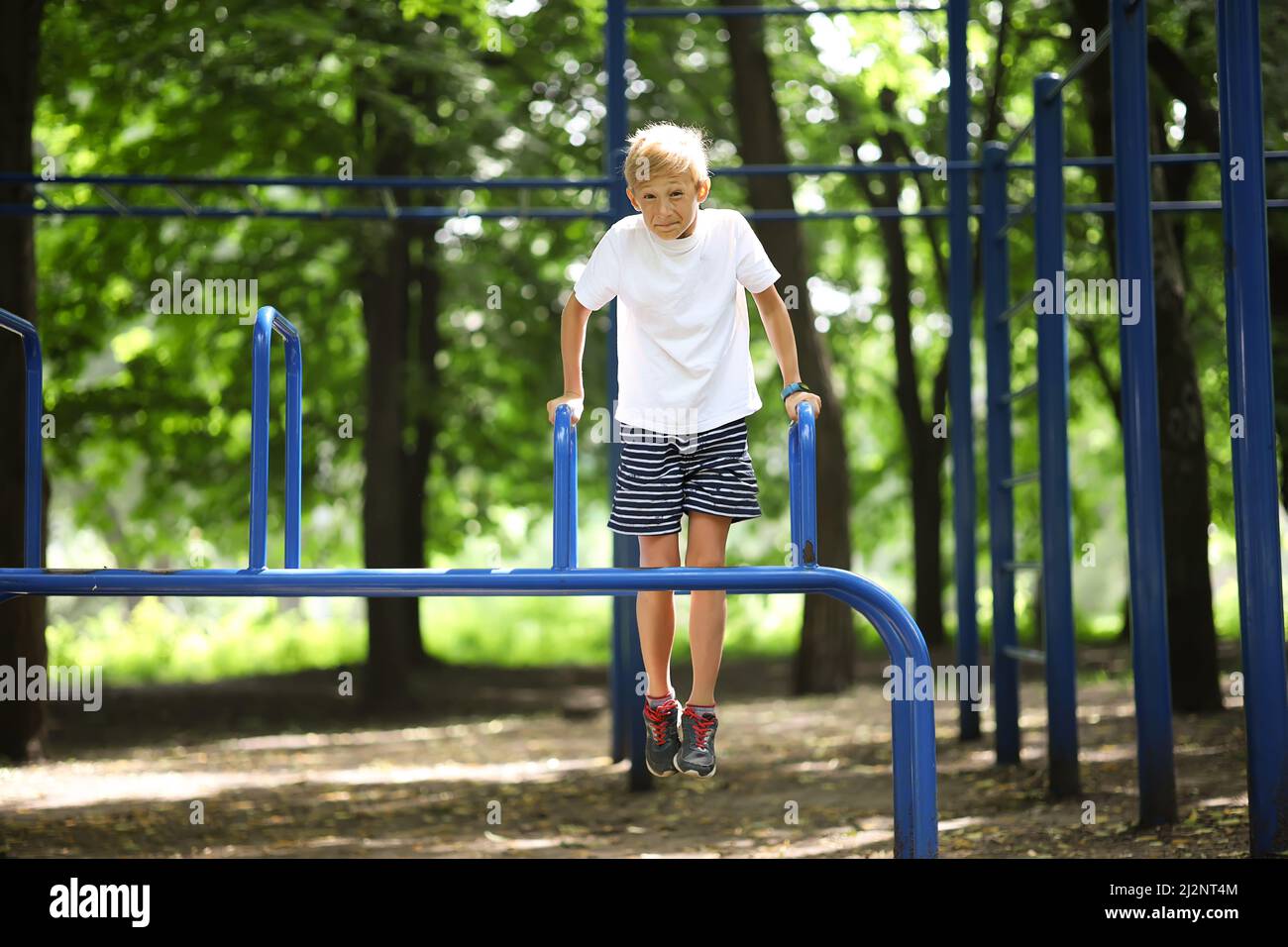 athlète garçon dans le parc accroché sur ses mains et fait des exercices sur les barres inégales Banque D'Images