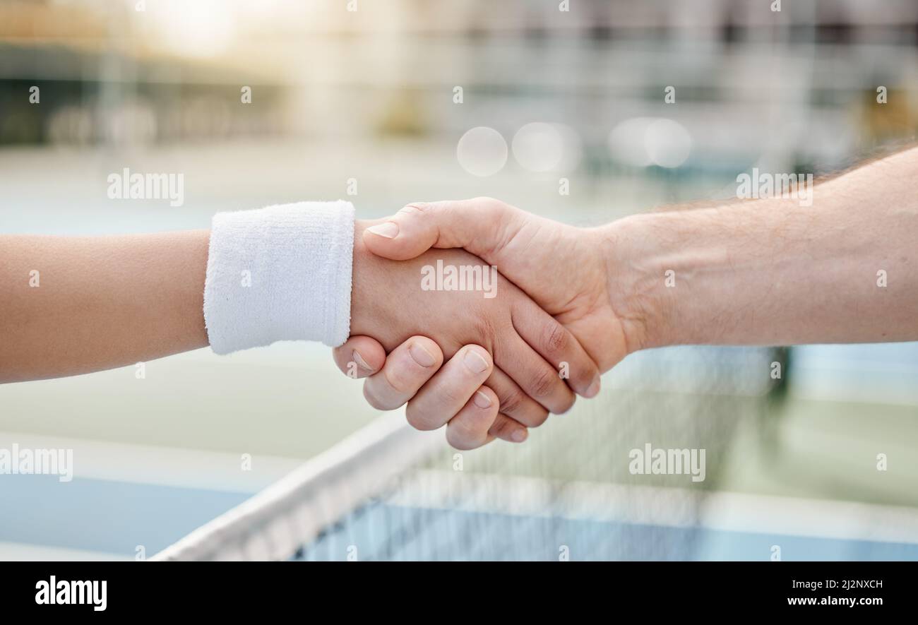 Beau jeu. Coupe courte de deux joueurs de tennis méconnus qui se secouent les mains tout en se tenant debout sur un court. Banque D'Images