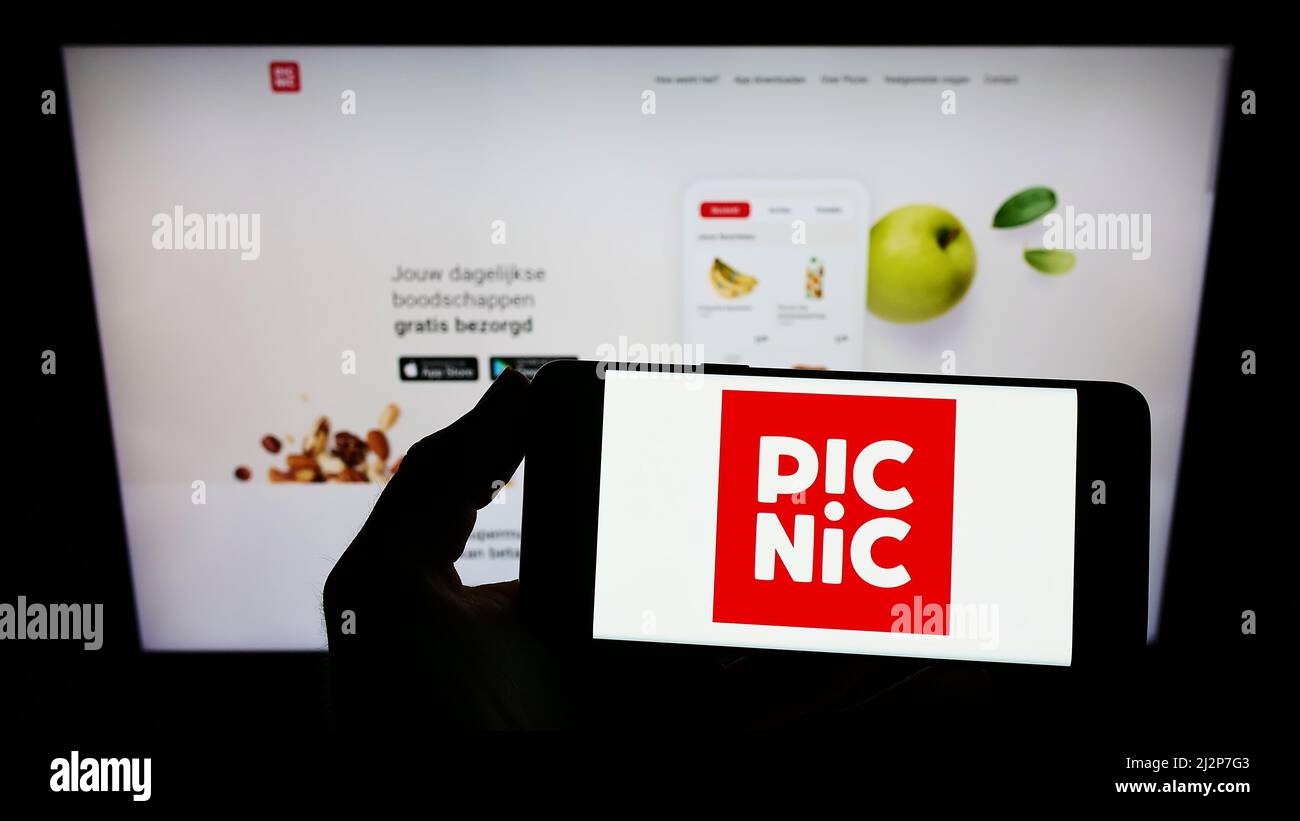 Personne tenant un smartphone avec le logo de la société néerlandaise de supermarché en ligne Picnic B.V. à l'écran devant le site Web. Mise au point sur l'affichage du téléphone. Banque D'Images
