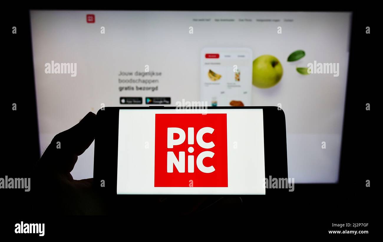 Personne tenant le téléphone portable avec le logo de la société néerlandaise de supermarché en ligne Picnic BV sur l'écran devant la page web d'affaires. Mise au point sur l'affichage du téléphone. Banque D'Images