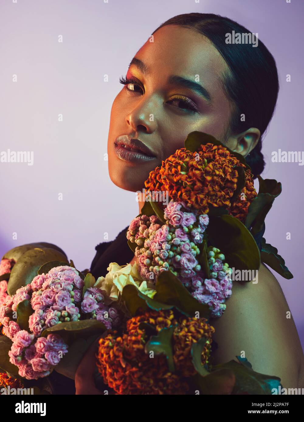 Un bel arrangement. Studio portrait d'une jeune femme attrayante posant avec un bouquet sur un fond coloré. Banque D'Images