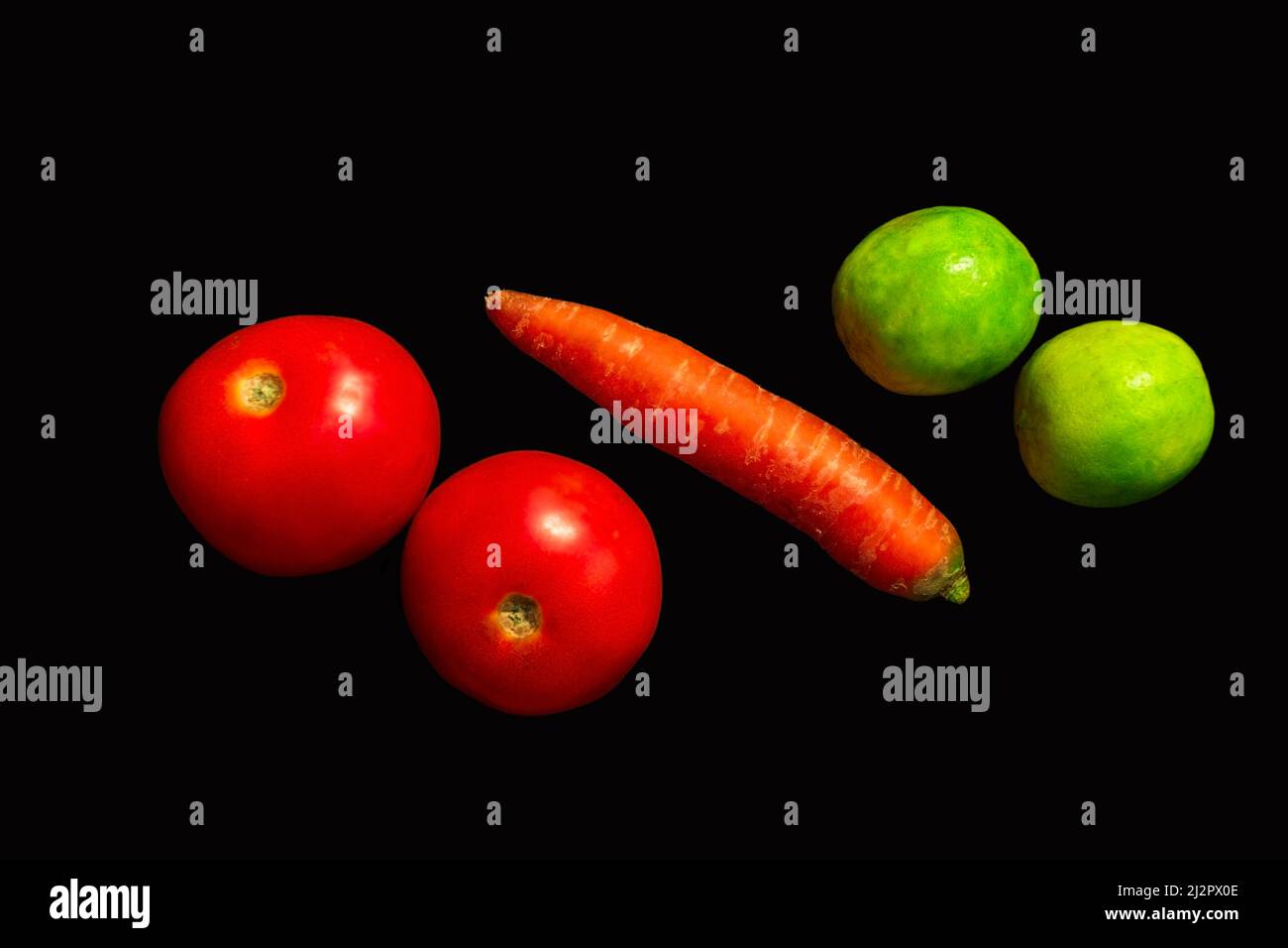 Tomates, carottes et citrons disposés sur fond noir isolé Banque D'Images