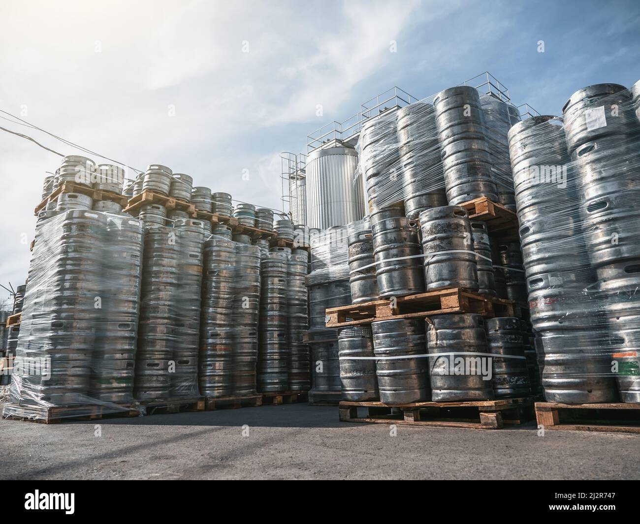 Fûts de bière. De nombreux fûts métalliques ou conteneurs pour brasserie dans des palettes empilées à l'extérieur. Banque D'Images