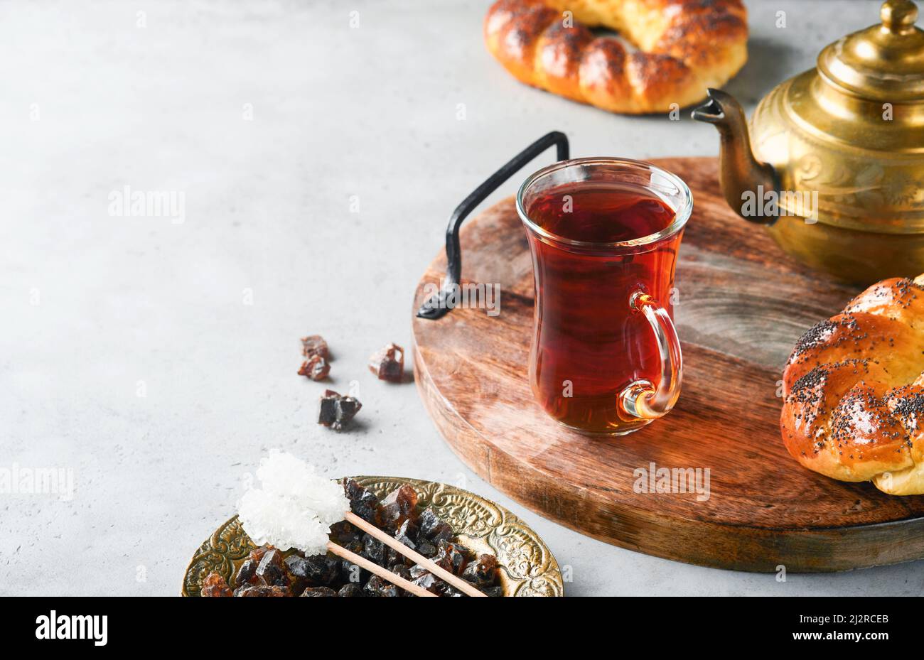 Thé noir turc. Tasse en verre de thé noir turc et bagel traditionnel turc croustillant sur fond de table en béton gris. Concept de pâtisserie pour le petit déjeuner. Tr Banque D'Images