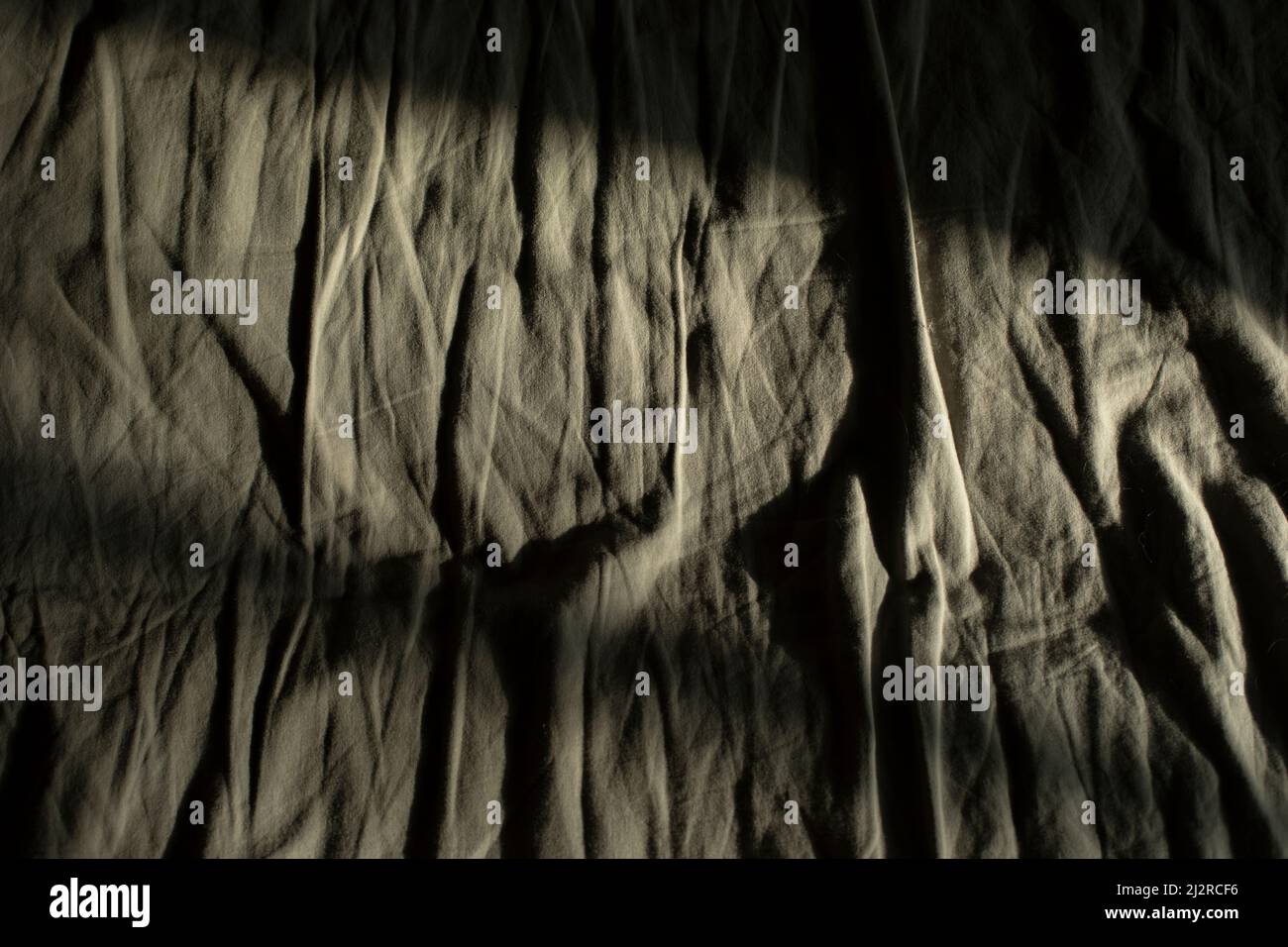 Linge de lit froissé. Tissu avec plis. Lumière sur la feuille. Lit du matin. Détails de la chambre. Banque D'Images