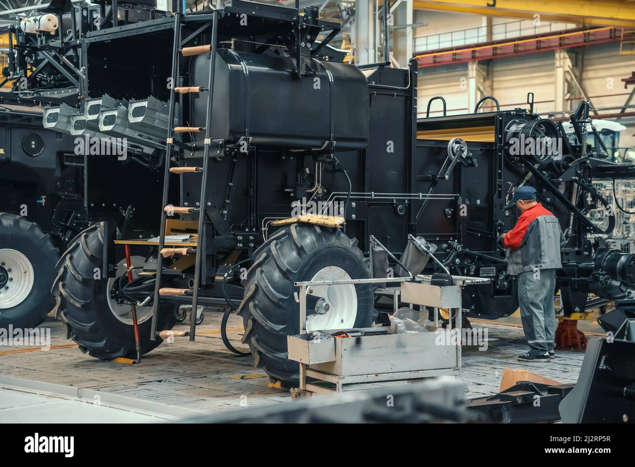 L'ouvrier assemble la moissonneuse-batteuse de véhicule agricole dans un atelier d'usine industrielle. Banque D'Images