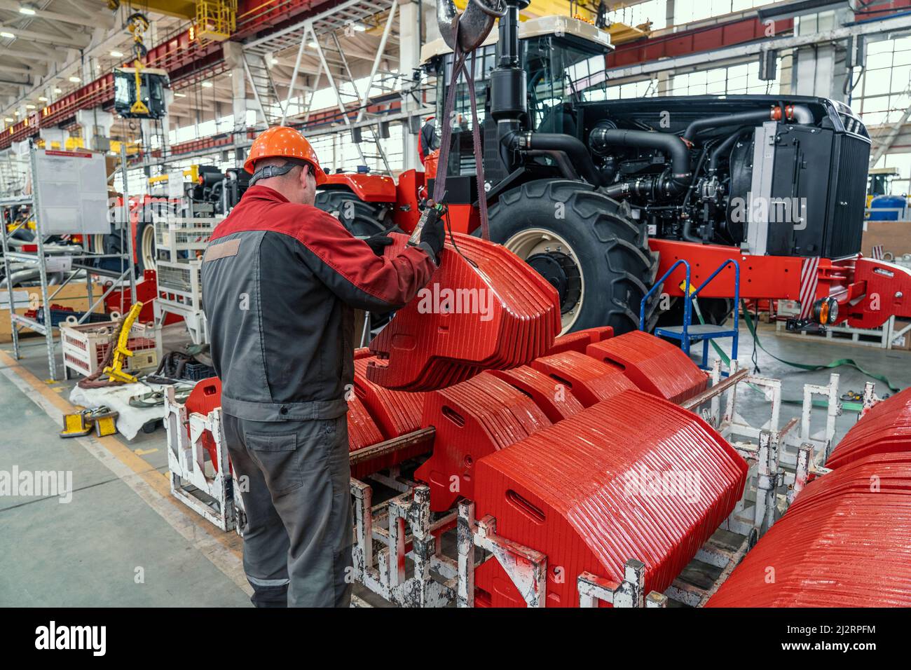 Un travailleur industriel assemble en usine de l'équipement agricole dans la chaîne de production de tracteurs ou de moissonneuses-batteuses. Banque D'Images
