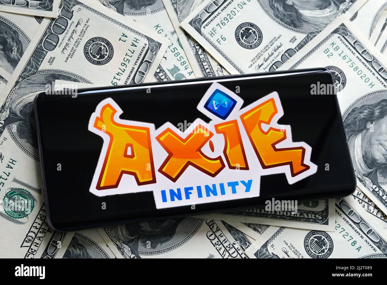 Axie Infinity NFT logo du jeu vu sur l'écran des billets de banque de smartphone et de dollar. Mise au point sélective. Concept. Stafford, Royaume-Uni, 3 avril 2022. Banque D'Images