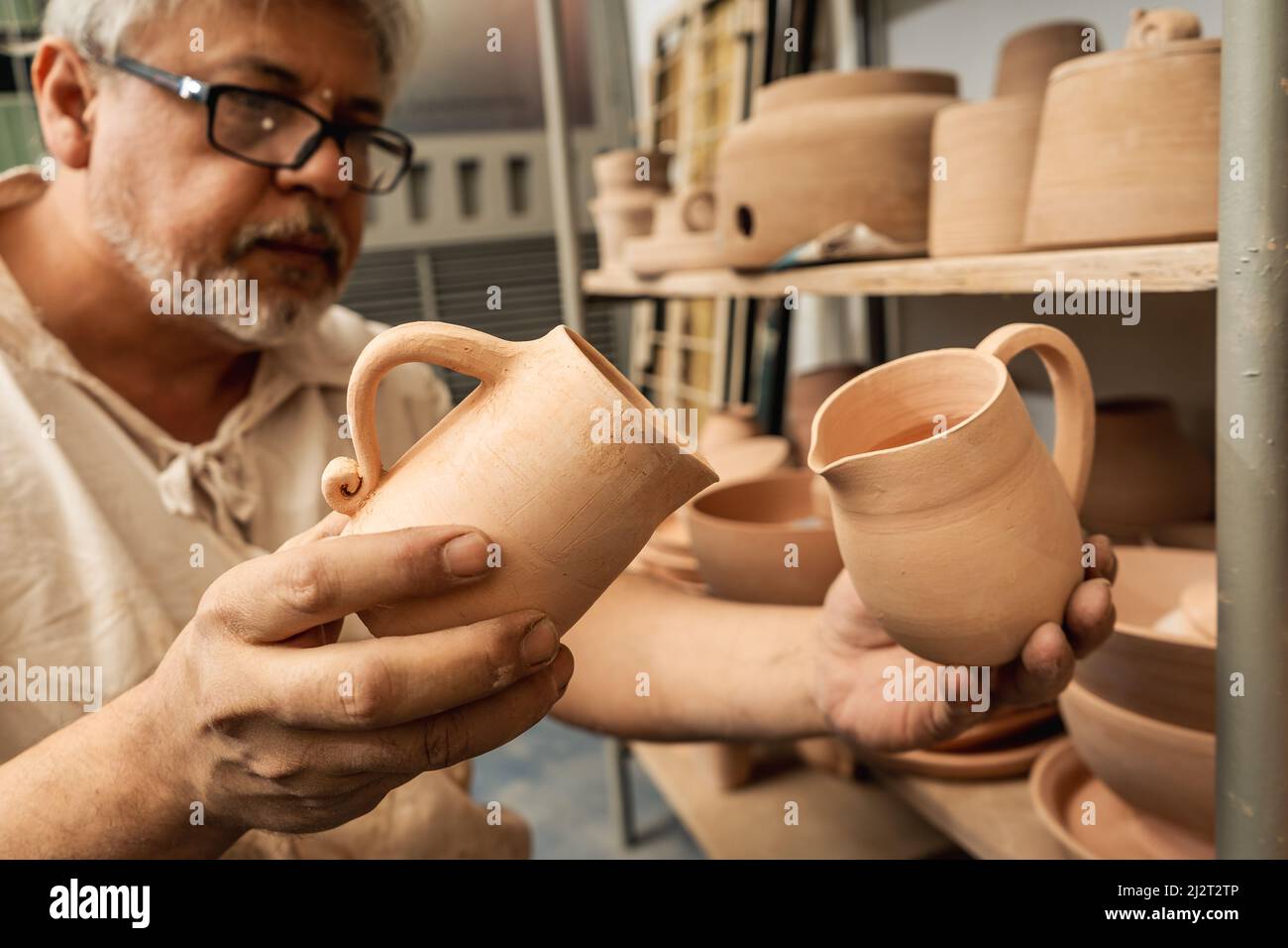 Artisan en poterie vérifiant les pots d'argile et organisant les étagères jusqu'à la peinture finale. Artisanat artisanal en argile. Banque D'Images