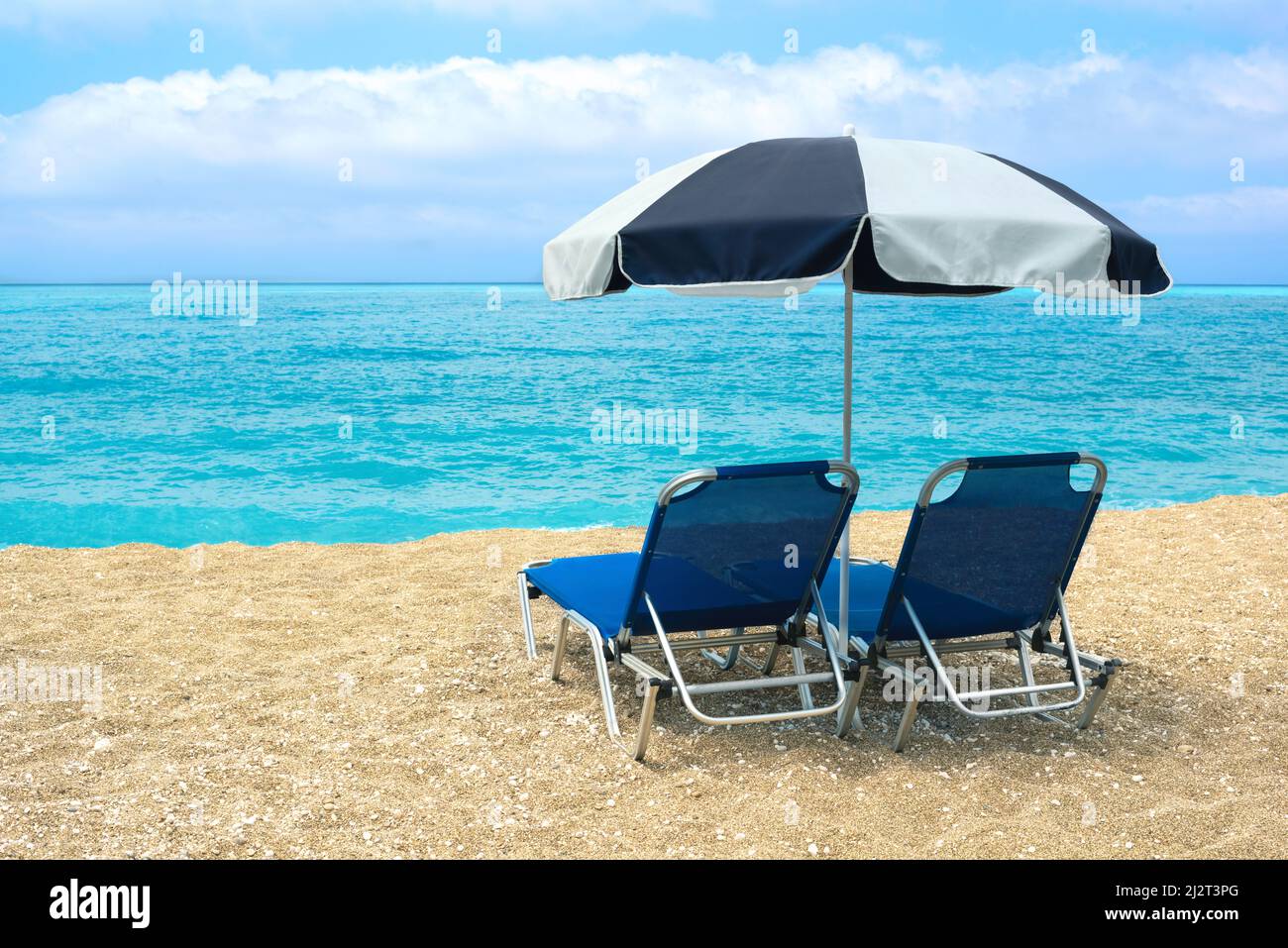 Plage vide avec deux chaises longues et parasol. Bleu azur et ciel incroyable. Banque D'Images