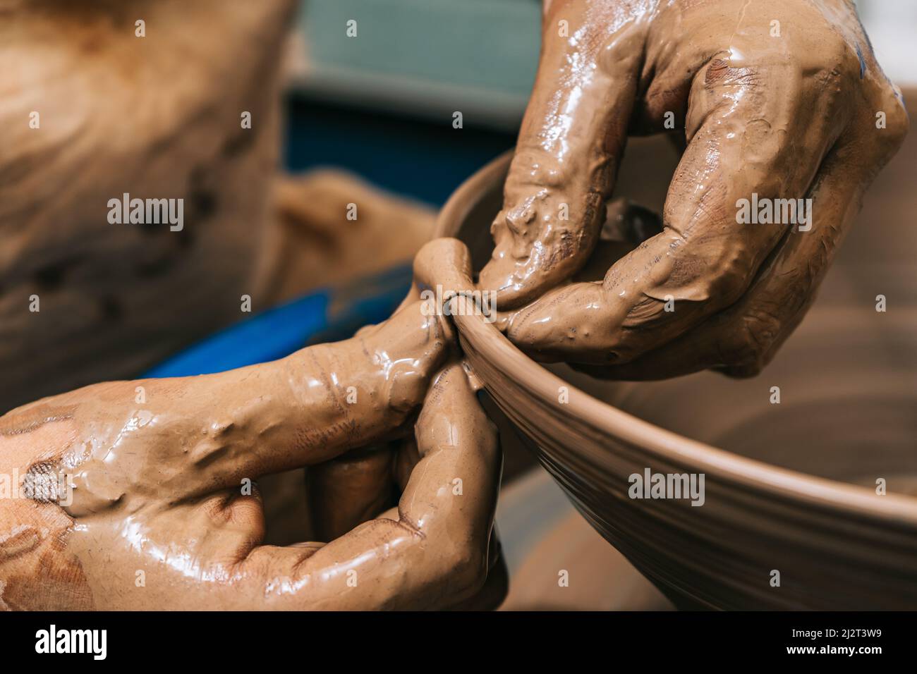 Les mains habiles d'une argile de travail de potier sur une roue de potier. L'argile prend la forme que le potier lui donne avec le ton de terre cuite de l'argile. Banque D'Images