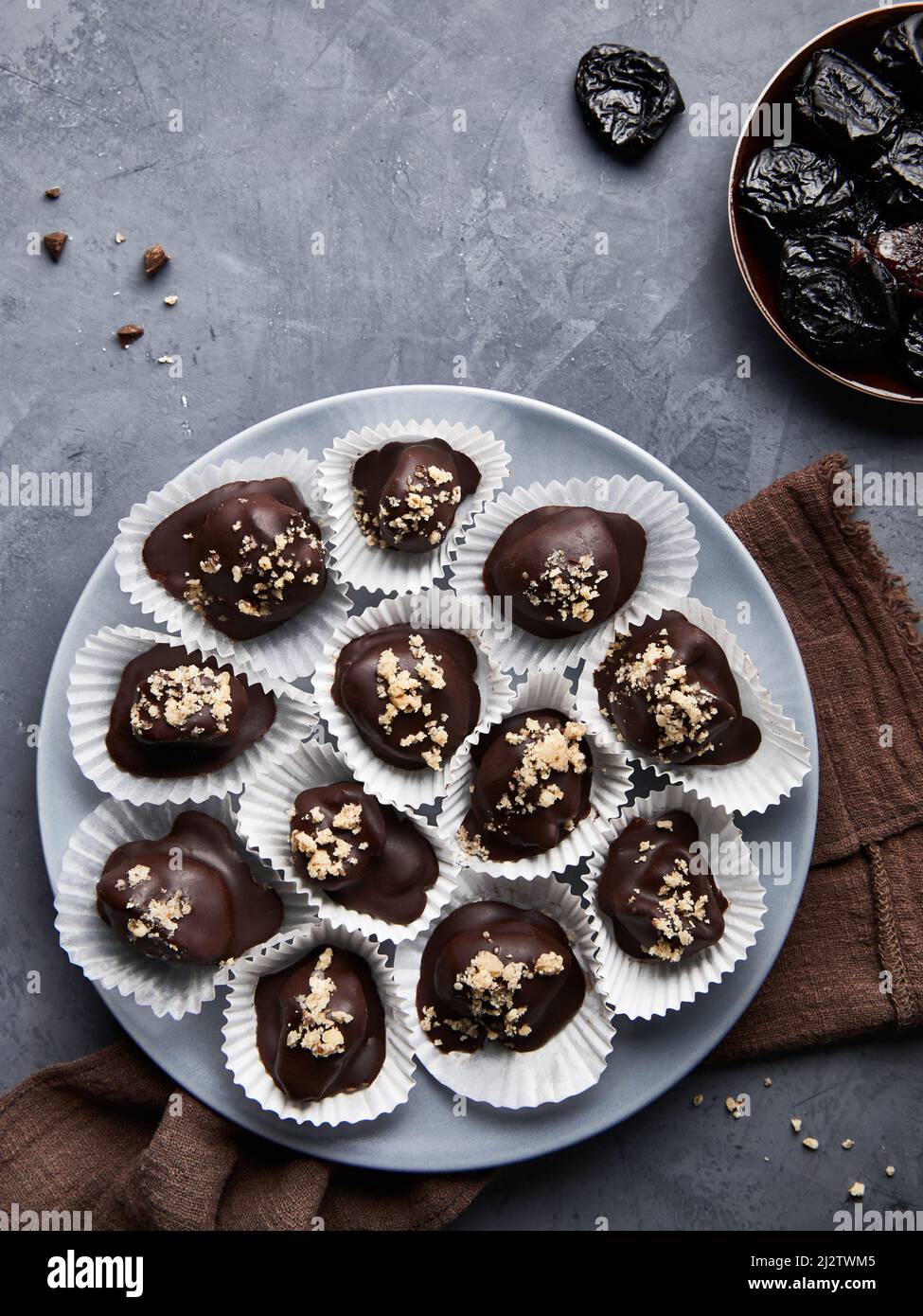 Bonbons au chocolat végétalien cru faits maison sans sucre, avec prunes séchées et noix sur fond bleu plat Banque D'Images