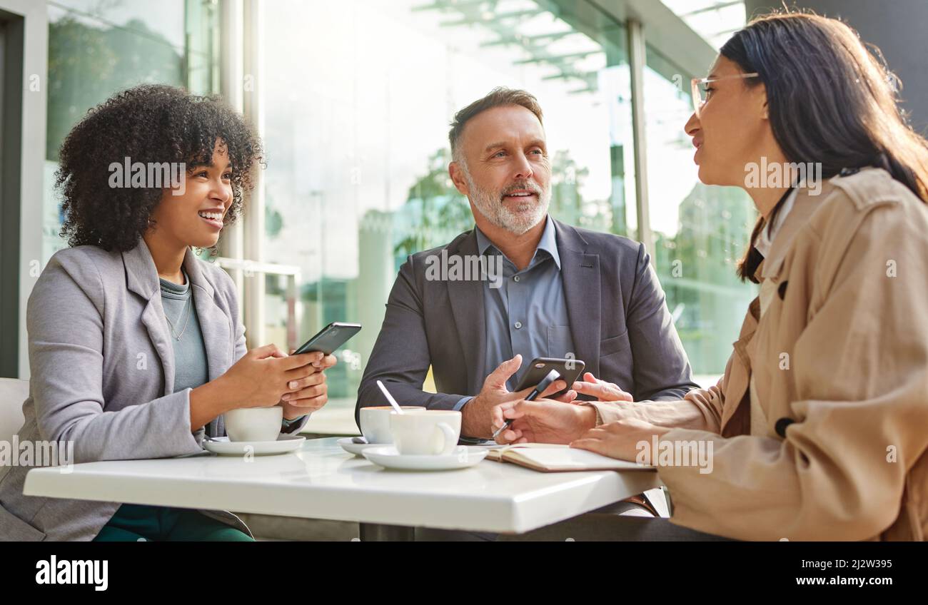 Quand avez-vous compris cela ? Photo d'un groupe de collègues qui remue des idées dans un café tout en utilisant leur smartphone. Banque D'Images