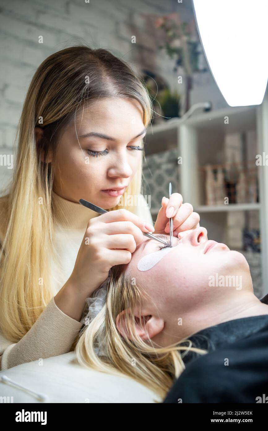 Procédure d'extension des cils dans le salon de beauté. Gros plan sur les cils. Concept spa Lash. Banque D'Images