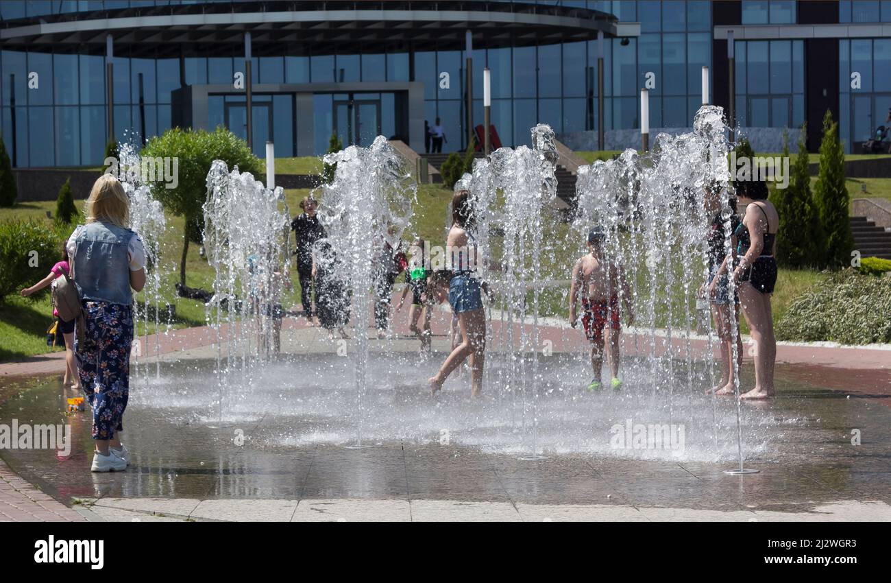 Minsk, Bélarus 08.06.2020. Les enfants s'amusent dans une fontaine sèche lors d'une chaude journée d'été. Les garçons courent parmi les jets d'une fontaine en fonctionnement. Banque D'Images