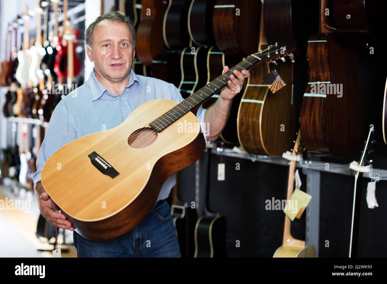 Homme mature qui choisit la guitare acoustique Banque D'Images