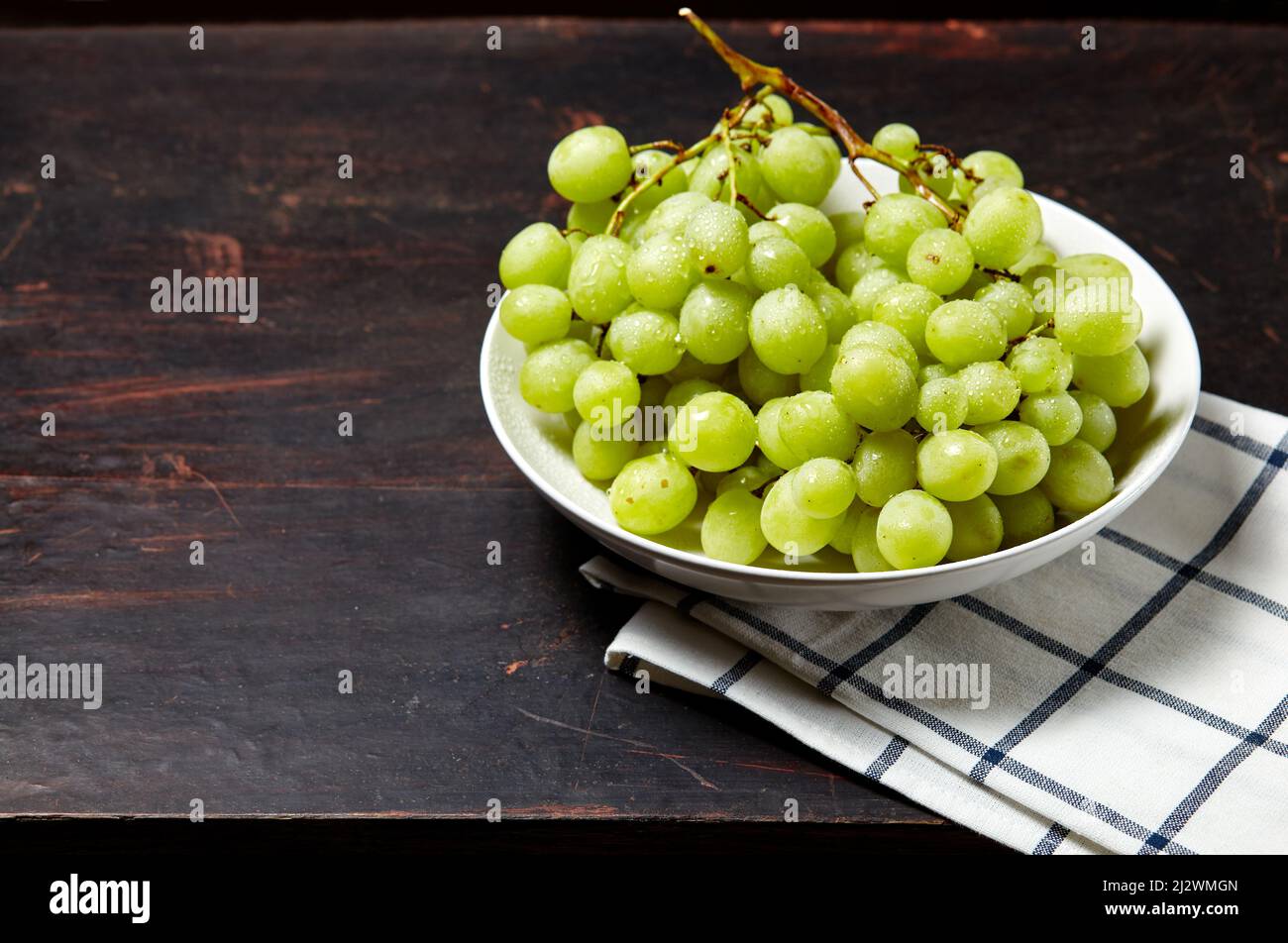 Branche de raisin vert mûr sur l'assiette avec gouttes d'eau. Raisins  juteux sur fond de bois, gros plan. Raisin sur table de cuisine sombre avec  espace pour copier Photo Stock - Alamy