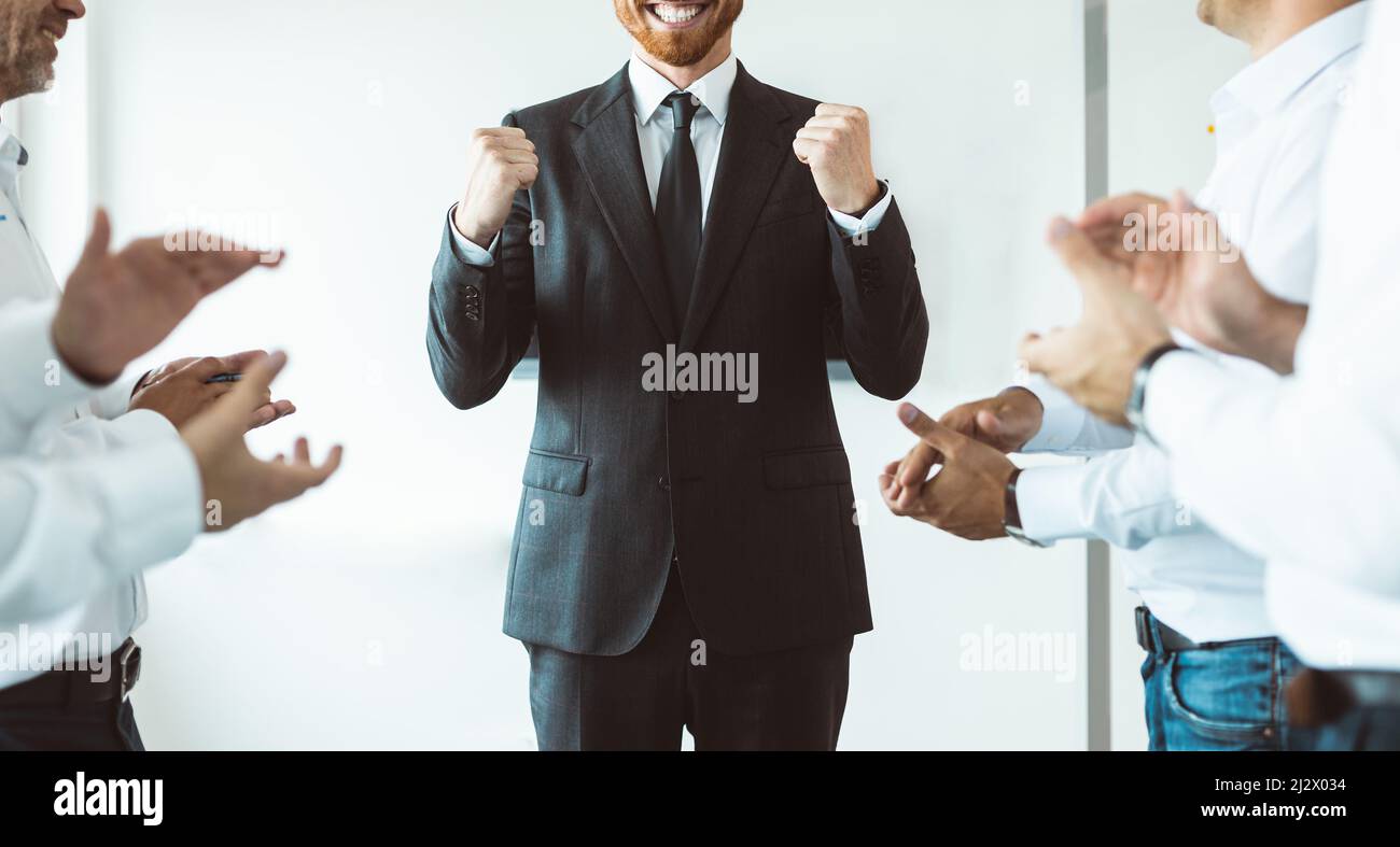 Le dirigeant de l'entreprise, entouré d'employés qui l'applaudissent, se réjouit du succès Banque D'Images