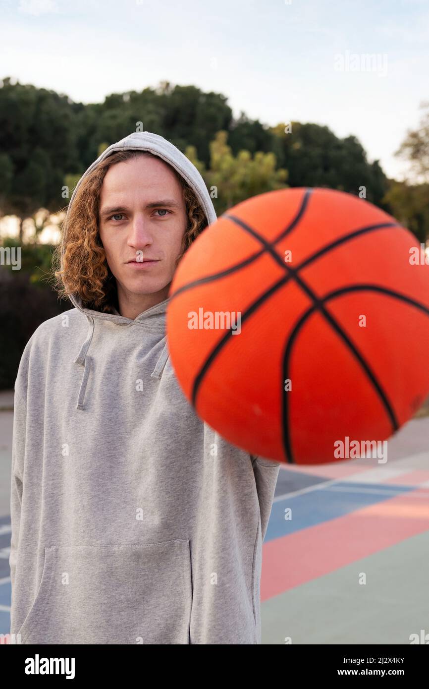 jeune homme tenant un ballon d'une main, se concentrer sur l'homme, concept de sport urbain dans la rue, espace de copie pour le texte Banque D'Images