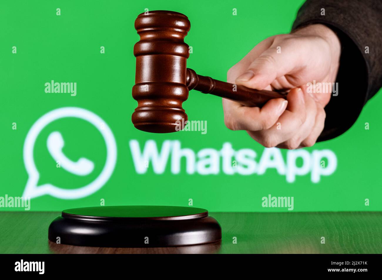 Gavel dans la main de juge contre le fond du logo de messager de Whatsapp. Le concept de procès. Banque D'Images