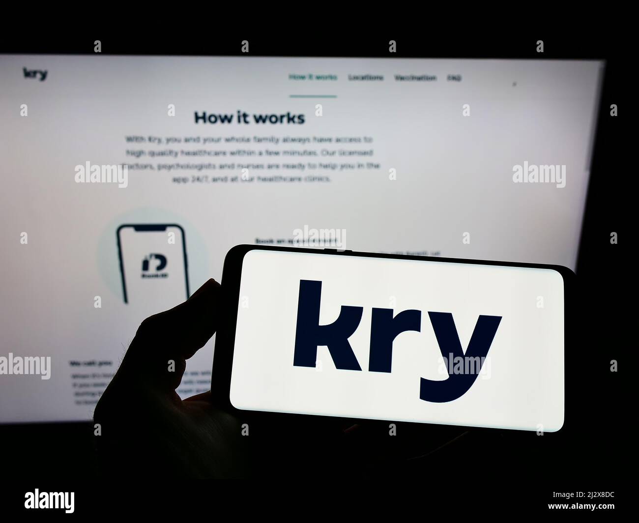Personne tenant un téléphone portable avec le logo de la société suédoise de soins de santé Kry International AB à l'écran en face de la page web. Mise au point sur l'affichage du téléphone. Banque D'Images