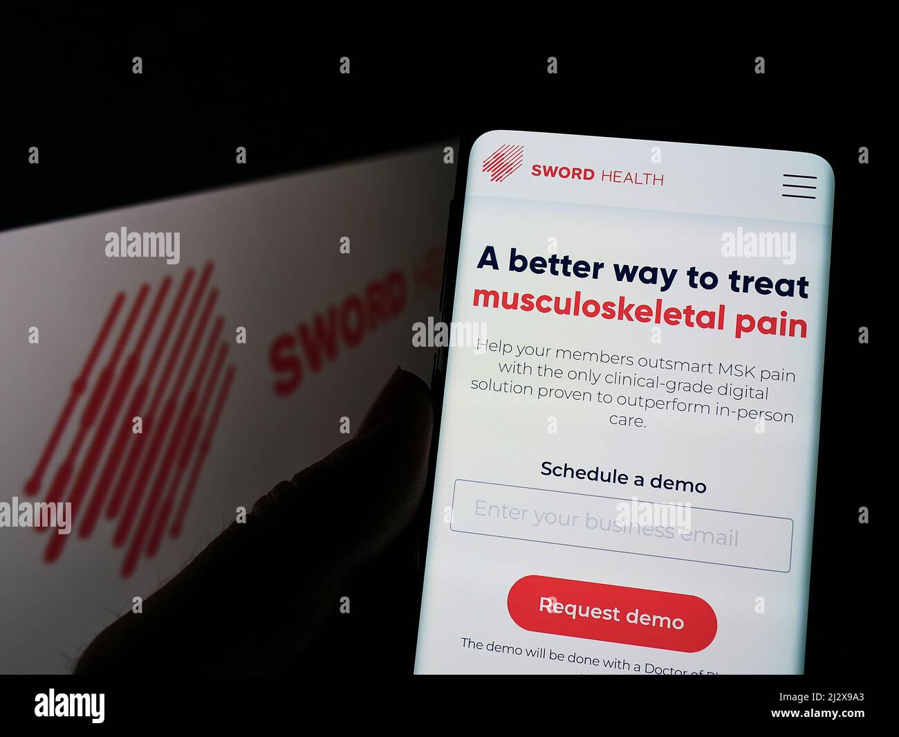 Personne tenant un smartphone avec la page Web de la société de santé électronique SWORD Health Inc. À l'écran devant le logo. Concentrez-vous sur le centre de l'écran du téléphone. Banque D'Images