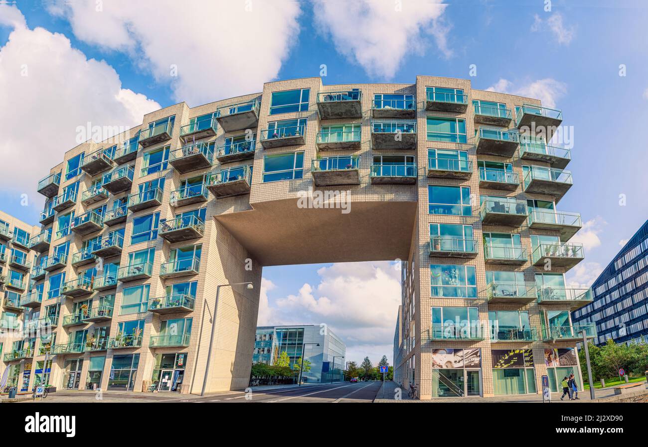 Un immeuble de bureaux moderne et une maison résidentielle avec une route asphaltée pour les voitures passant par une arche dans la zone Ørestad. Copenhague, Danemark Banque D'Images
