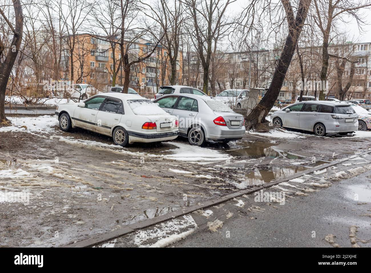 Russie, Vladivostok, 21 mars 2022. Voitures dans un parking sale après la neige. Les zones pauvres de la ville et les problèmes d'infrastructure. Transport et véhicules. Banque D'Images