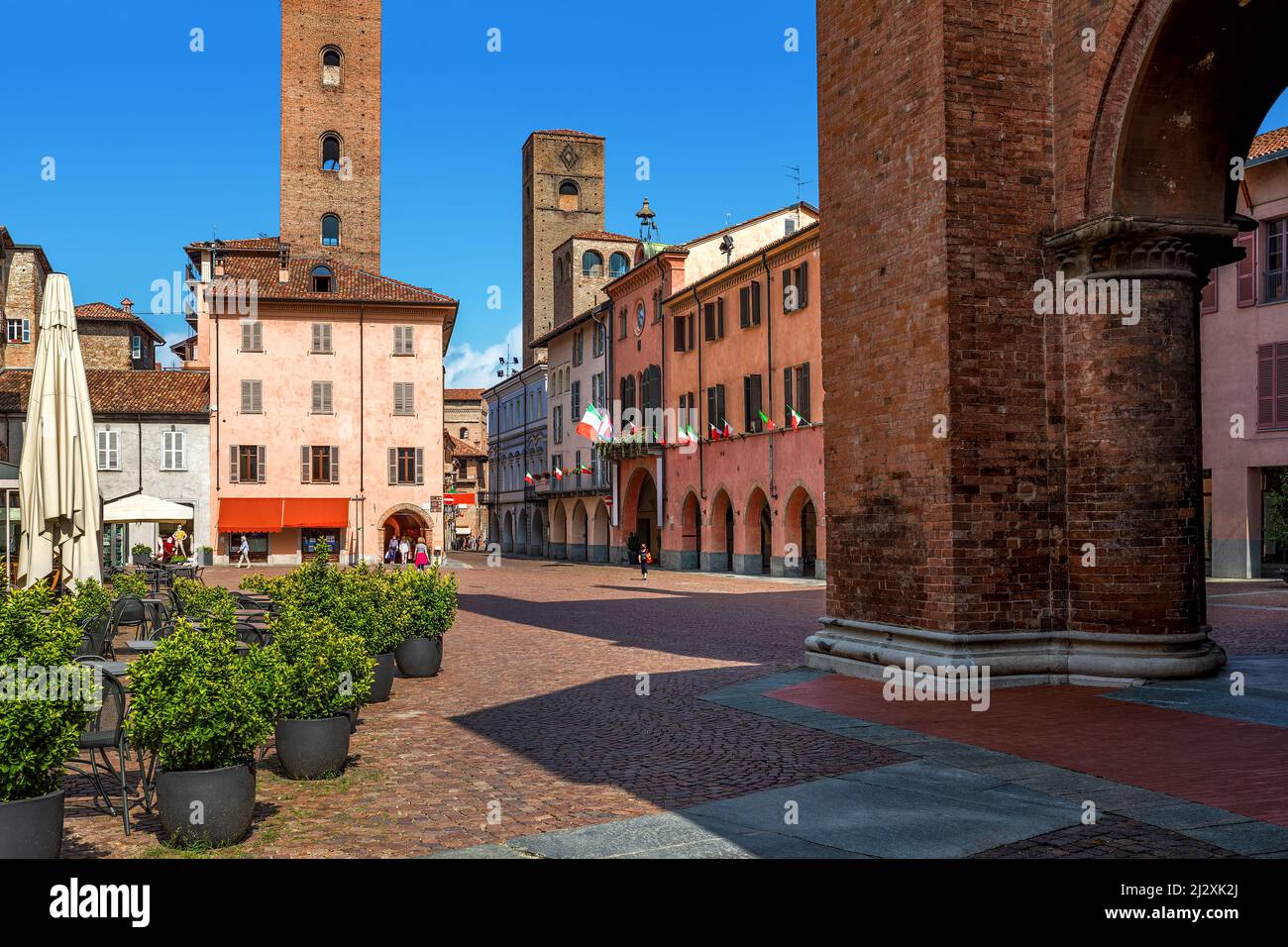 Place pavée entourée de maisons historiques et de tours médiévales dans la vieille ville d'Alba, Piémont, Italie du Nord. Banque D'Images