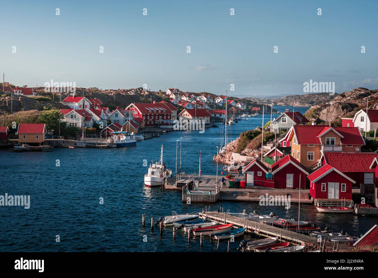 Port et côte dans le village de Kyrkesund sur l'archipel de Tjörn sur la côte ouest de la Suède, ciel bleu avec le soleil Banque D'Images