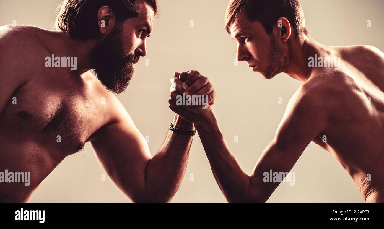 Homme barbu fortement musclé bras luttant un homme faible et puny. Bras luttant main mince, gros bras fort en studio. Deux mains d'homme ont classé le bras luttant Banque D'Images