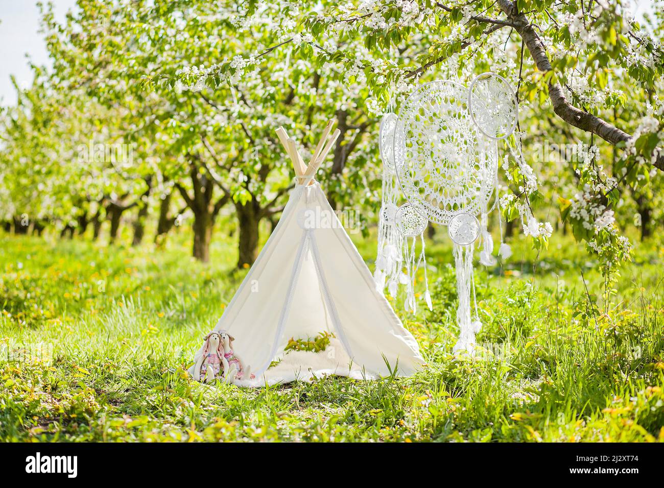 Zone photo pour une séance photo d'enfant dans un jardin en fleurs - wigwam, crocheted de rêve de Catcher et jouets de lapin Banque D'Images