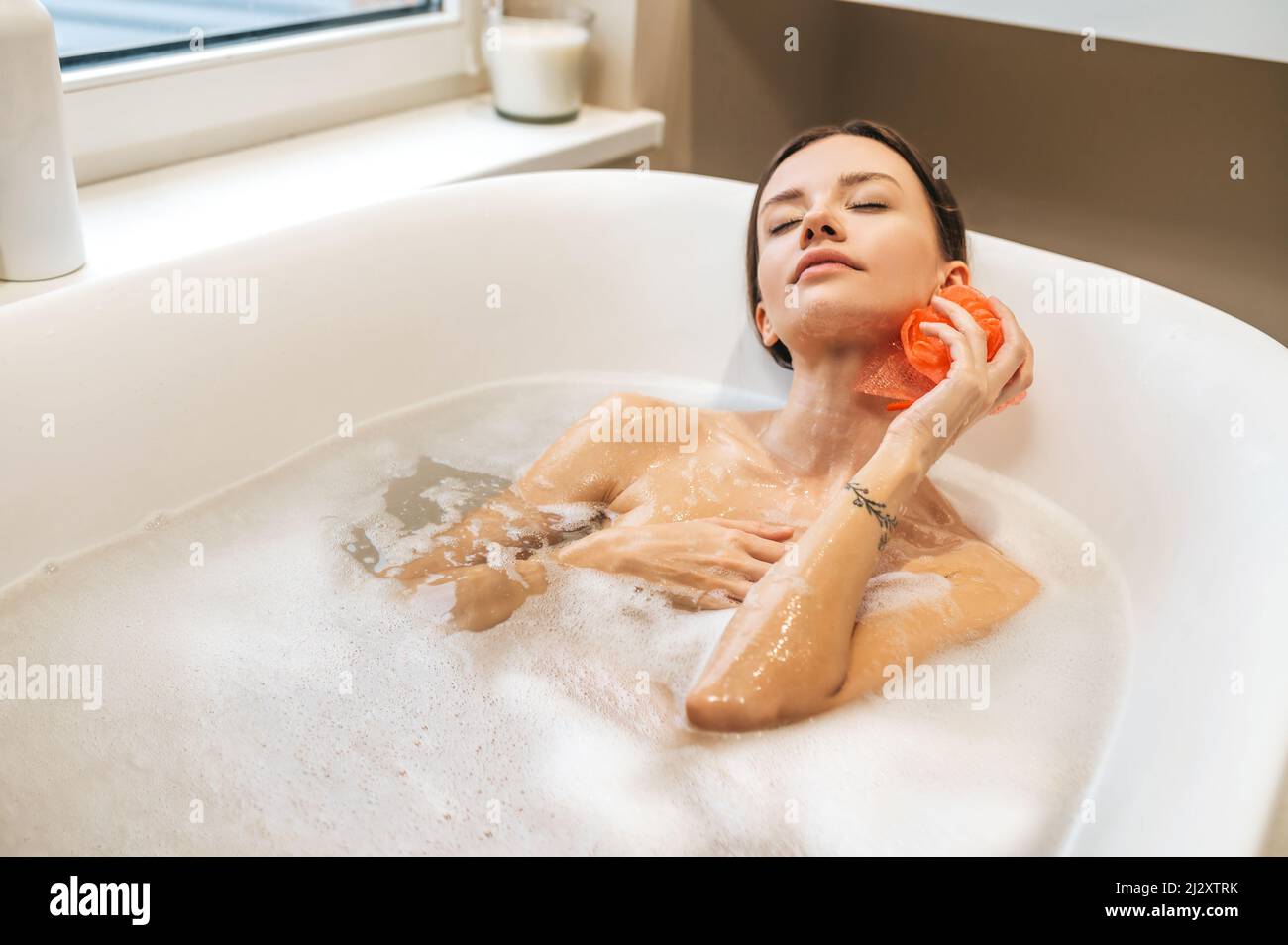 Une jeune femme paisible se baignant dans la baignoire Banque D'Images
