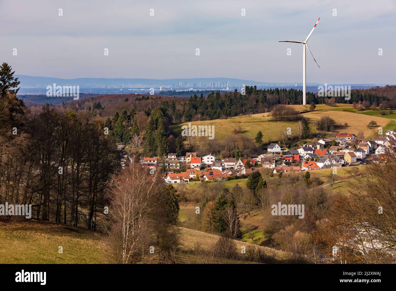 Un paysage rural avec un village, une éolienne et la vue lointaine de la ville de Francfort Banque D'Images